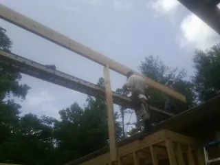 Carpenter setting a ridge beam over a new addition frame — Ice Dam Removal by Roofing Brothers in Rose Creek
