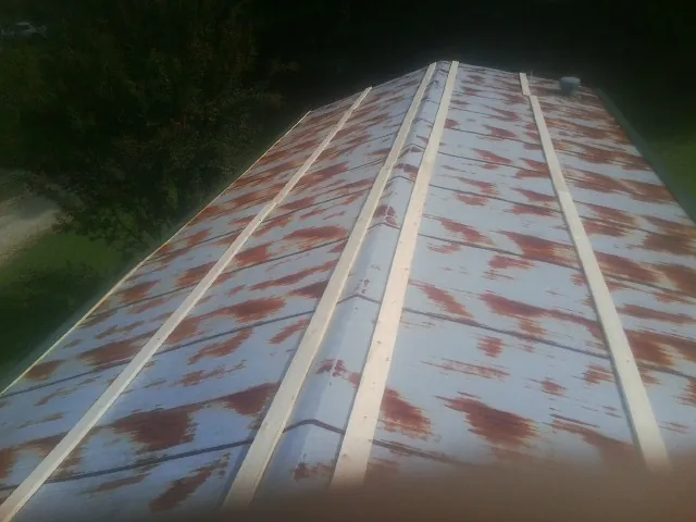 Rusted metal roof panels with new wood purlins before replacement — Storm Damage Roof Repair in Rose Creek by Roofing Brothers