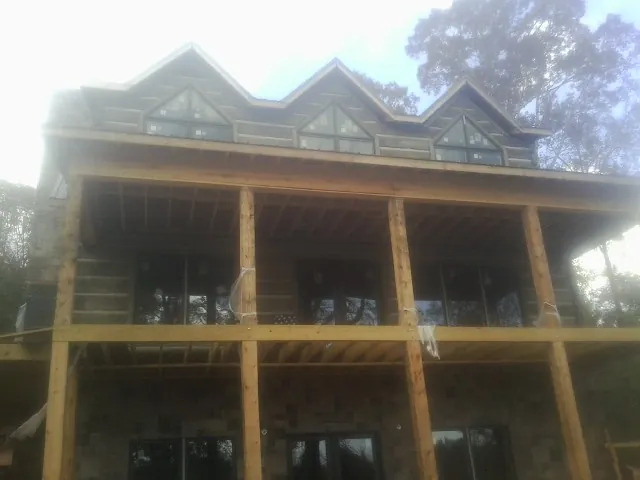 Dormers and porch framing on a large log home under construction — Roof Coating work by our crew in Rose Creek