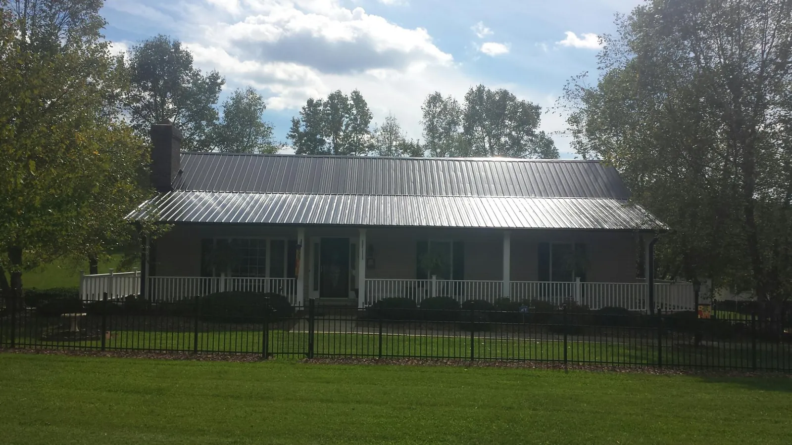 Gray metal roof on a brick ranch with a full width front porch — Gutter Guard Installation work by our crew in Rose Creek