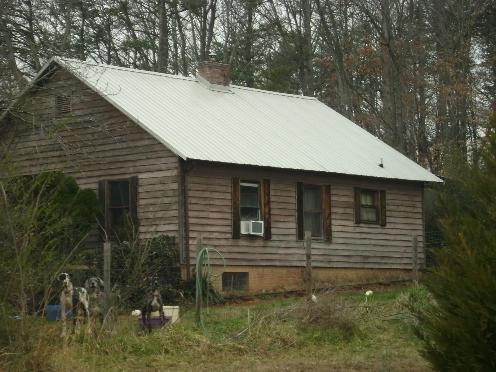 White metal roof on an old wood sided farmhouse, from a Metal Roof Installation job in Rose Creek